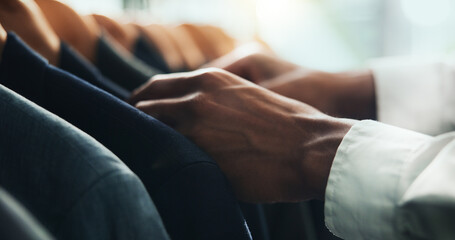 Hands, businessman and choice for clothes shopping with blazer check, fabric quality and customer experience. Person, rack and decision for professional collection, suit wardrobe and fashion industry