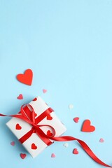 Gift box with red hearts on color background