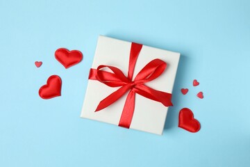 Gift box with red hearts on color background