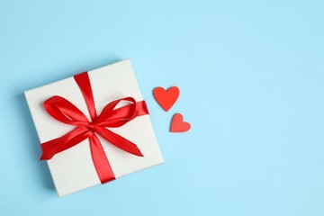 Gift box with red hearts on color background