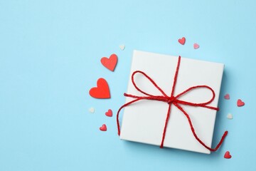 Gift box with red hearts on color background