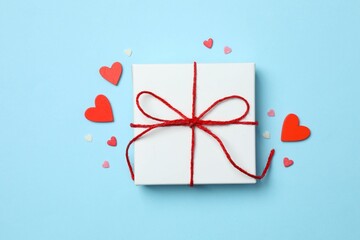 Gift box with red hearts on color background