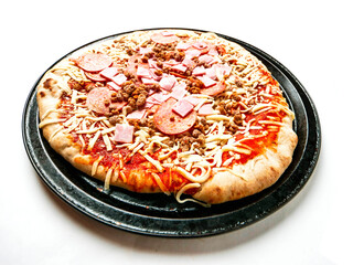 A pizza with pepperoni and ham on it. The pizza is on a black rusty metal tray. The pizza is ready to cooked, White background. Popular Italian style dish made with fine, high quality products.