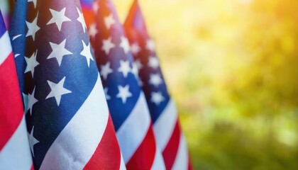 Obraz premium Close-Up View of Vibrant American Flags Waving Outdoors on a Sunny Day with Golden Light and Greenery in the Background. Perfect for Celebrating Patriotic USA Holidays, Memorial Day, or July 4th Event