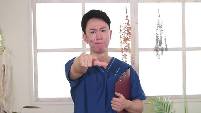 指を差すスクラブ姿の若い男性の医療従事者
