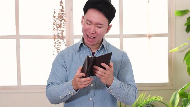財布を持ち困る私服姿の若いアジア人男性