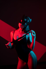 Sensual Woman in a Cat Mask Wields a Whip in a Dramatic Playroom Setting Capturing the Essence of BDSM and Adult Fantasies