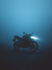 A motorcycle beams through dense fog at night, creating a dramatic and mysterious scene with a blue hue.