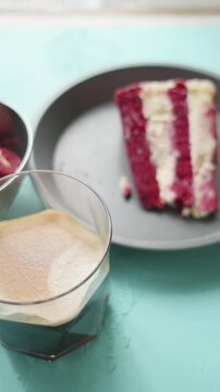 red velvet cookie and red velvet cheesecake next to americano on wooden background with cinnamon sticks