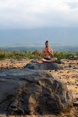 Man Practicing Yoga Meditation Outdoors in Nature with Mountain View.