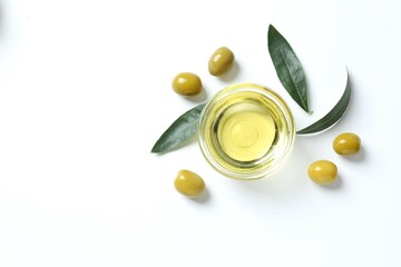 Bowl of fresh olive oil and olives with leaves on white background