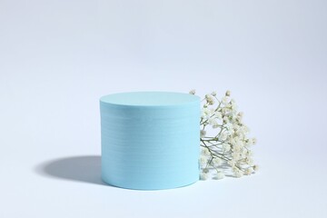 Podium and white gypsophila flowers on color background