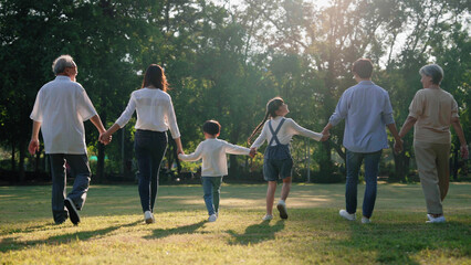 Back view of happy Asian family walking in the park, Outdoor with big family and summer season...