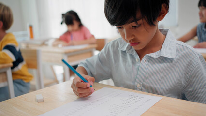 Elementary school student boy are sitting in the classroom at school and doing final exams in mathematics