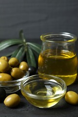 Bowl of fresh olive oil and olives with leaves on wooden background