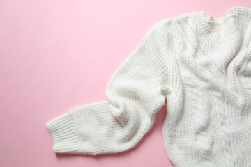 White knitted sweater on paper color background top view copy space. Texture of woolen cotton winter autumn cozy sweater, clothes. Knitted jumper, pullover, fashion. Sweater close-up