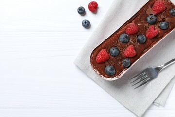 Delicious tiramisu cake with berries on table