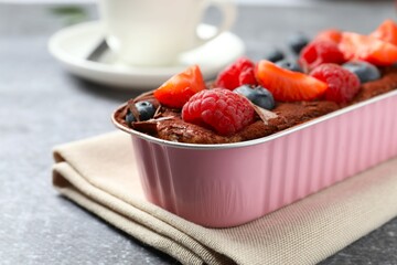 Delicious tiramisu cake with berries on table