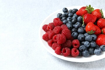 Different fresh ripe berries in bowl on the table