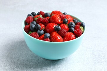 Different fresh ripe berries in bowl on the table