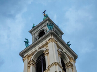 Historic Church Tower with Angel Statues and Cross Against Cloudy Sky