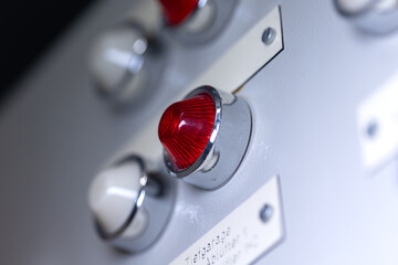 Close-up of a white and red signal lamp on a power distributor of a heating system. Analog device,...