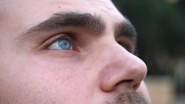 A young bald man with a short beard looks up to the sky, reflecting on past mistakes and contemplating