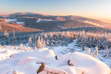 Eastern Sudetes, View of snowy mountain range from hiking trail during winter hike in the mountains, viewpoint of wide winter landscape in the mountains at sunset.
