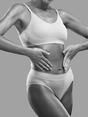 Fototapeta premium A slender swarthy woman in underwear on a white background. Healthy lifestyle, sport and diet.