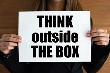 Think outside the box. Woman with white page, black letters. Inspiration, new ideas, motto,...
