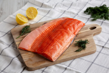 Organic Raw Salmon Fillet on a wooden board, side view.
