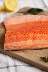 Organic Raw Salmon Fillet on a wooden board, side view.