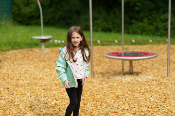 Little cute smiling girl without a tooth plays on the playground. Happy childhood concept