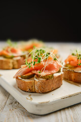 Delicious open-faced sandwiches with smoked salmon and fresh toppings on a wooden platter