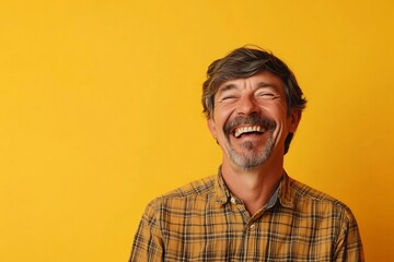 Obraz premium Cheerful Man Laughing Joyfully Against Vibrant Yellow Background