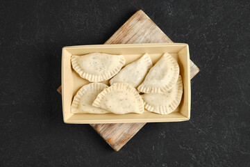 Overhead view of freshly prepared dumplings in cardboard box on a wooden board
