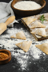 Freshly made ravioli on a kitchen counter with flour and spices