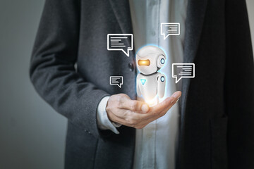 A man is holding a robot in his hand. The robot is surrounded by speech bubbles. The robot is white and has a blue face