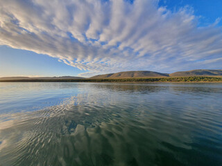 Crystal-blue river that reflects the blue sky and clouds