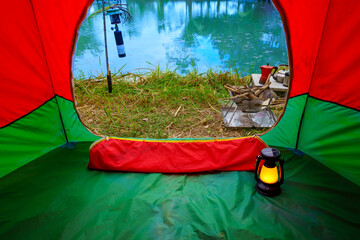 Looking out from the inside of the tent, resting equipment for setting up a camping tent in the forest in the morning, camping tents with outdoor coffee-making facilities