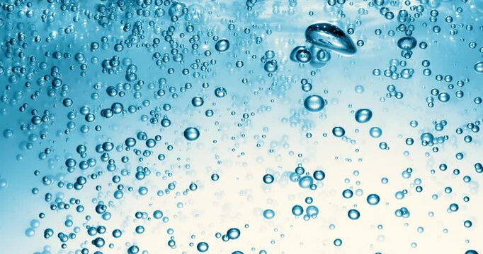 Many water bubbles in blue water close up, abstract water wave with bubbles in slow motion.
