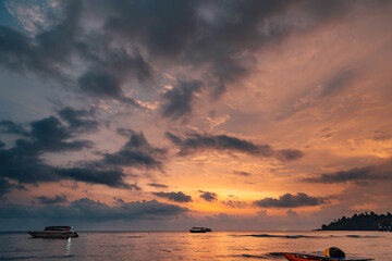 Sky with clouds above tropical beach at colorful sunset