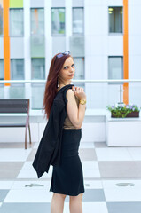 Portrait of a beautiful woman walking in the city. She is wearing a black dress and her chic hair is combed back. Leisure concept.