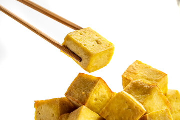 Fried tofu cubes on a plate with chopsticks. organic vegetarian tofu.  soy beans.Vegan food ingredient in Asian cuisine, Plant based diet. food concept.. Chinese food