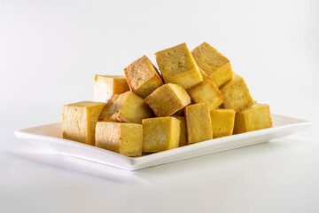 Fried tofu cubes on a plate with chopsticks. organic vegetarian tofu.  soy beans.Vegan food ingredient in Asian cuisine, Plant based diet. food concept.. Chinese food