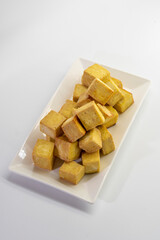 Fried tofu cubes on a plate with chopsticks. organic vegetarian tofu.  soy beans.Vegan food ingredient in Asian cuisine, Plant based diet. food concept.. Chinese food