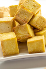 Fried tofu cubes on a plate with chopsticks. organic vegetarian tofu.  soy beans.Vegan food ingredient in Asian cuisine, Plant based diet. food concept.. Chinese food