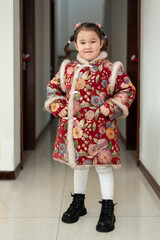 Small Chinese, multiracial girl is ready for a celebration of Chinese New Year. She is posing for a photo in her traditional Chinese dress