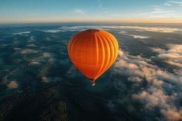 Orange hot air balloon floating over foggy landscape at sunrise