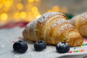 Fresh croissant with blueberries on a Christmas New Year background.